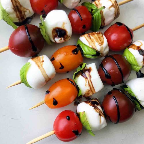 Several keto friendly skewers with tomato, cheese, drizzled oil